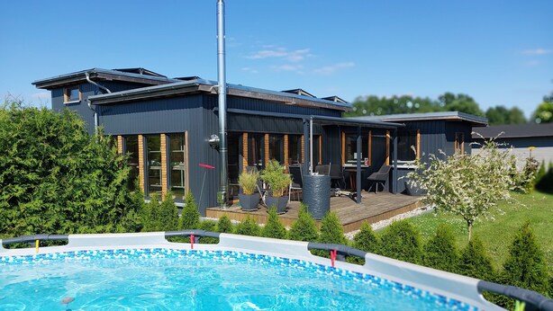 A modern house with a pool, outdoor seating, and a tall chimney. - Holiday Home 'Happy-Nest' sauna pool air conditioning Wi-Fi fireplace barbecue (Oberkrämer)