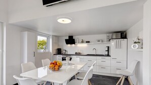 A modern kitchen with white cabinets, a dining table with chairs, and a fruit bowl. - Holiday Home 'Happy-Nest' sauna pool air conditioning Wi-Fi fireplace barbecue (Oberkrämer)