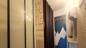 Ein Flur mit einer Tür, die ein Bergmotiv zeigt, einem 'HOME'-Schild und einem Kleiderständer.