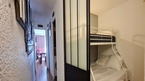 Ein schmaler Flur, der zu einem Zimmer mit Etagenbett führt.