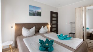 Quarto com uma cama grande, mesa de cabeceira, cadeira, guarda-roupa e espelho.