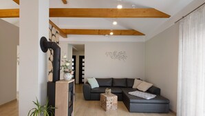 Uma sala de estar moderna com um sofá seccional, uma mesinha lateral, um vaso de planta e um detalhe decorativo na parede.