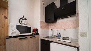 Una cocina compacta equipada con microondas, cafetera, fregadero y un refrigerador pequeño.