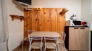 Una cocina compacta con pared de madera, un microondas, un hervidor y un mueble pequeño.