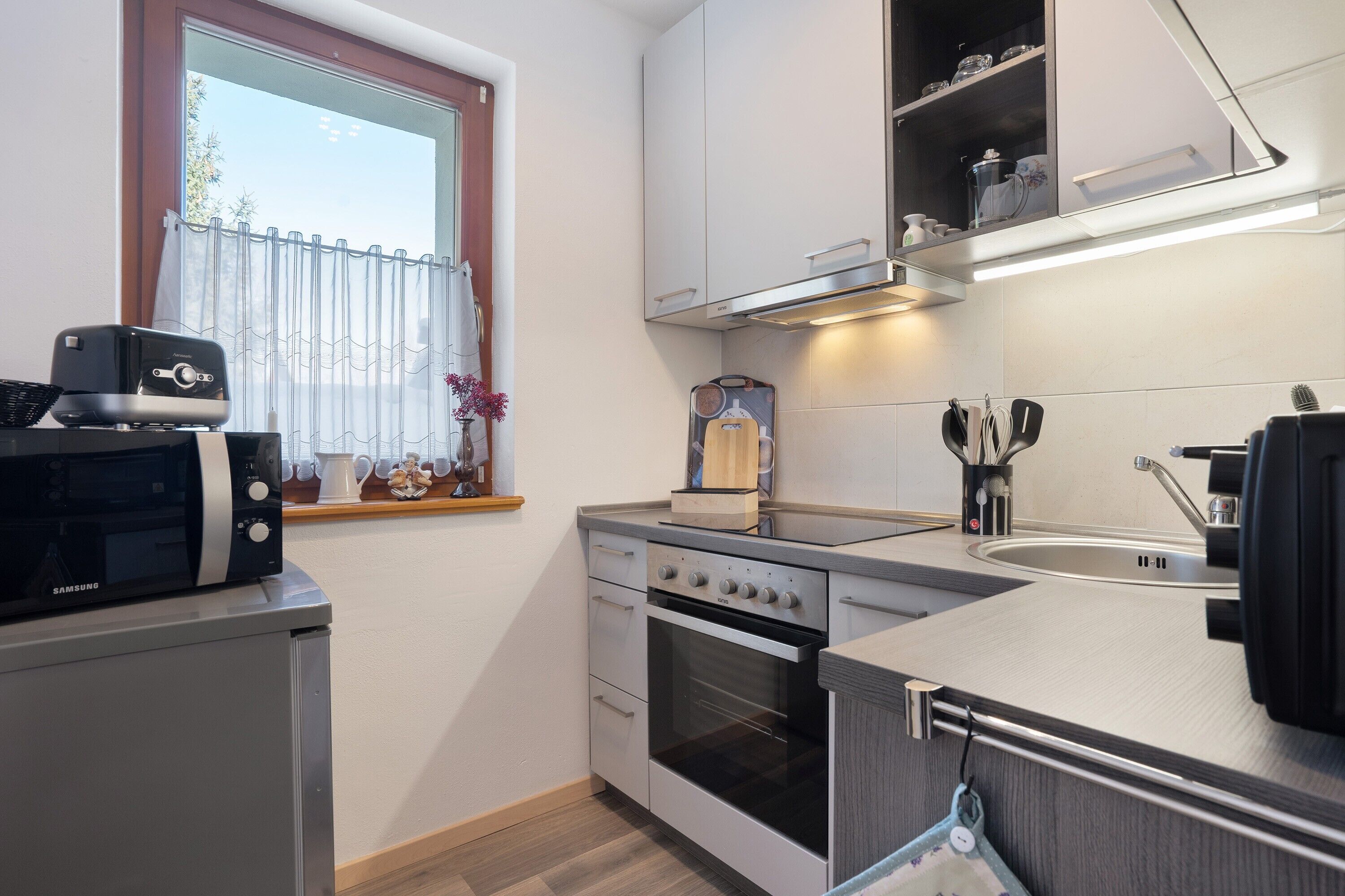 A compact kitchen with a microwave, oven, and sink.
