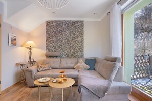 En stue med sofa, lampe, bord og en væg med mønster.