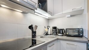 A modern kitchen with a stove, sink, toaster, and coffee maker. - Apartment 'Spreequartier' with Lake View, private Terrace and Wi-Fi (Malschwitz)
