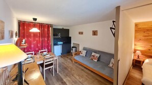 Ein kompakter Wohnbereich mit Essplatz, Küchenzeile und einer Couch mit Kissen.