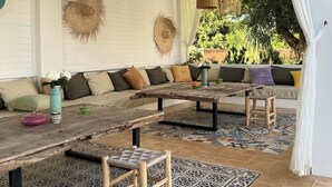 A cozy outdoor seating area with a thatched ceiling, woven wall hangings, and a patterned floor. - A haven of peace in the countryside surrounded by 90 olive and 10 argan trees (Essaouira)