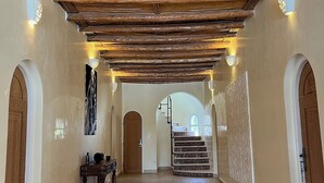 A hallway with a wooden ceiling, a rug, and a staircase leading to another room. - A haven of peace in the countryside surrounded by 90 olive and 10 argan trees (Essaouira)