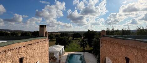 Una terraza en la azotea con piscina, mobiliario exterior y vistas al campo.