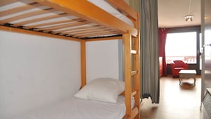 Una cama litera en una habitación con vistas a un balcón y una silla roja.