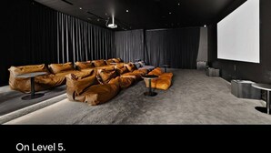 Uma sala de cinema com assentos escalonados, uma tela grande e um projetor.