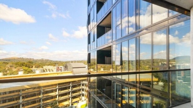 Um edifício moderno com grandes janelas e vista para um parque de estacionamento.
