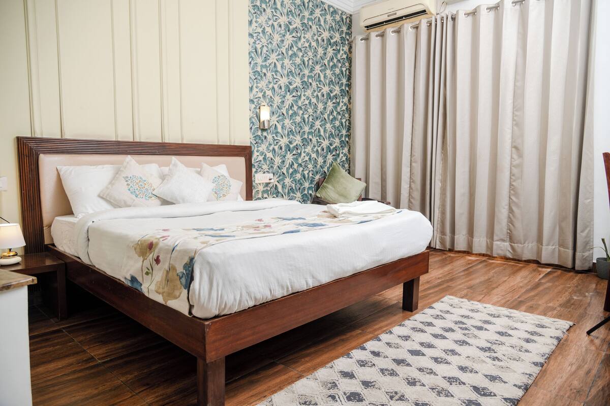 A bedroom with a wooden bed, a patterned wall, and a window with curtains.