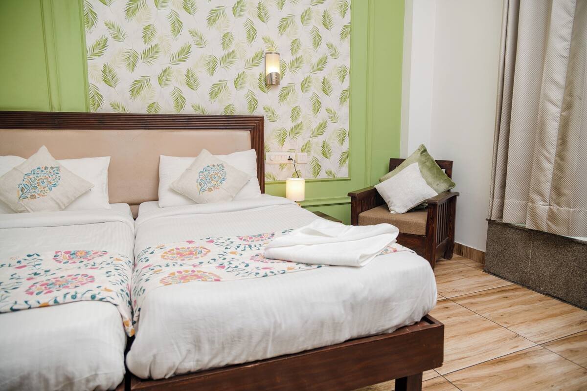 A double bed with floral bedding, a nightstand with a lamp, and a green accent wall.