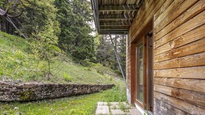 A wooden cabin with a stone retaining wall and a grassy slope. - Stay with Garden, Chamrousse (Chamrousse)