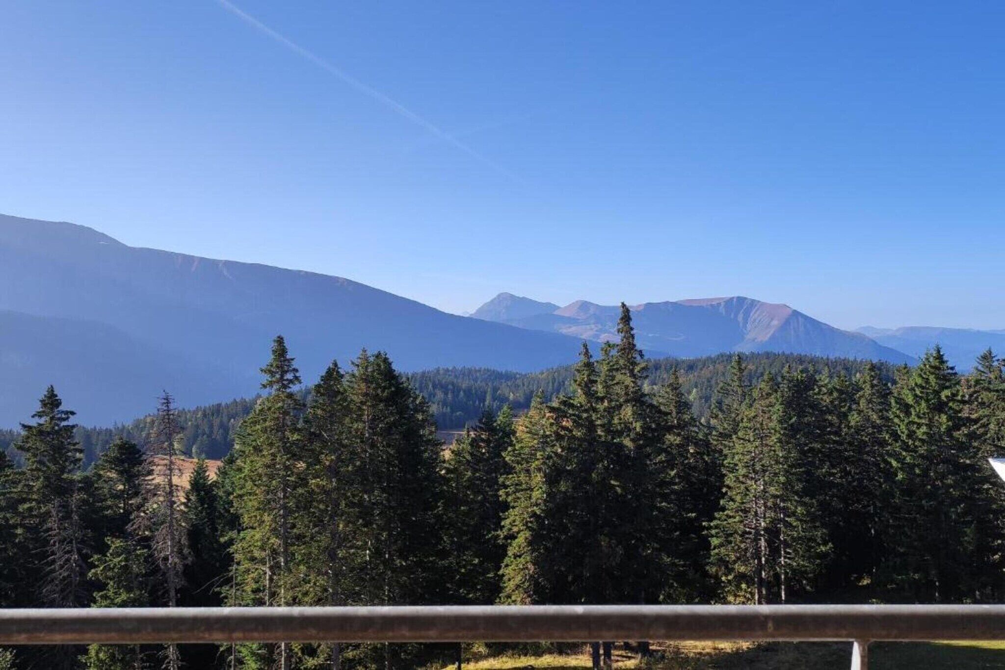 A mountain landscape with dense forests and a clear sky.