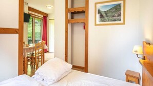 A bedroom with a bed, a wooden headboard, a small bedside table, a lamp, and a framed picture on the wall. - Stay with Garden, Chamrousse (Chamrousse)