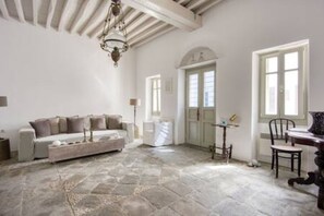 A room with a stone floor, a sofa, a table, and a chair.