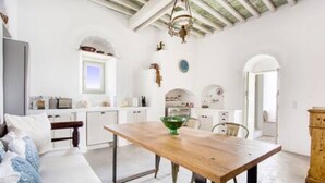 A modern kitchen with white cabinetry, a wooden dining table, and a chandelier.