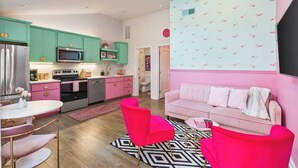 A modern kitchen with teal cabinets, a pink sofa, and a geometric patterned rug. - Barbie Dream Condo - Near Restaurants, Coffee & Bar (Nashville)