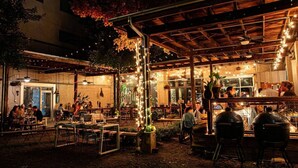 An outdoor dining area with tables and chairs, string lights, and a covered section with a ceiling fan. - Barbie Dream Condo - Near Restaurants, Coffee & Bar (Nashville)