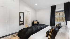 A bedroom with a large bed, a mirror, a door, and a window with curtains. - Vibrant Neon Condo Near Restaurants, Coffee & Bars (Nashville)