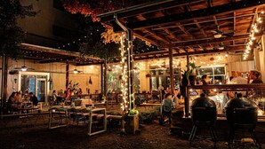 An outdoor dining area with tables and chairs, string lights, and a covered section with a grill. - Vibrant Neon Condo Near Restaurants, Coffee & Bars (Nashville)
