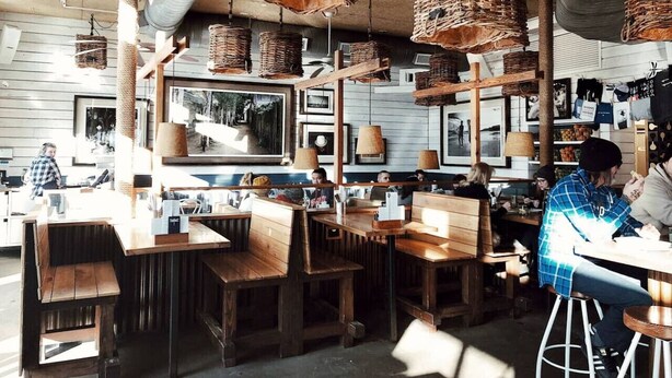 A restaurant with wooden tables and chairs, hanging wicker baskets, and framed pictures on the walls. - Vibrant Neon Condo Near Restaurants, Coffee & Bars (Nashville)