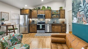 Cocina moderna con armarios de madera, electrodomésticos de acero inoxidable y un comedor con sofá y sillas estampadas.