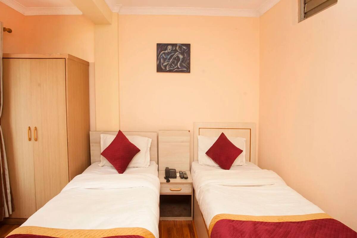 A double bed room with two bedside tables, a wardrobe, and a painting on the wall.
