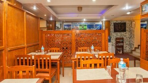 A restaurant with wooden furniture, a travel information center, and a decorative wall. - Hotel Mountain Gateway (Kathmandu)