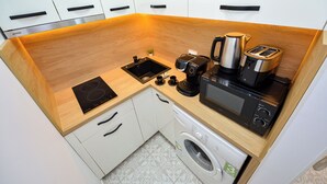 Cocina compacta con lavamanos, estufa, tostadora, cafetera y lavadora.