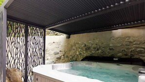 A hot tub area with a stone wall and a metal fence.