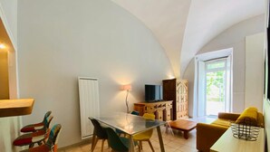A compact living space with a dining table, chairs, a sofa, a television, and a cabinet.