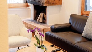 A living room with a fireplace, a sofa, a chair, a coffee table, and a potted plant.