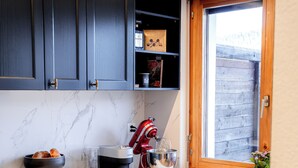 A modern kitchen with dark cabinets, a marble countertop, and a red stand mixer.