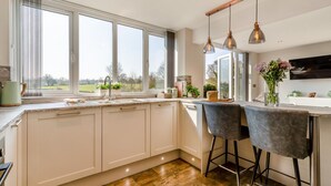 A modern kitchen with a large window, a sink, and a bar area with two chairs.