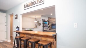 Eine Küche mit Bar, hölzernen Barhocker und einem Schild mit der Aufschrift 'FARMHOUSE'.