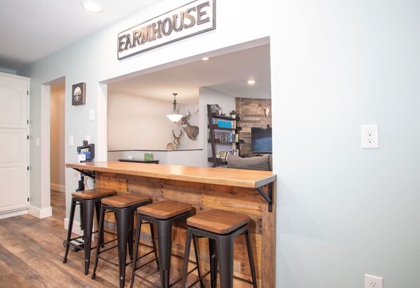 Une cuisine avec un coin bar, des tabourets en bois et une enseigne sur laquelle on peut lire « FERME ».