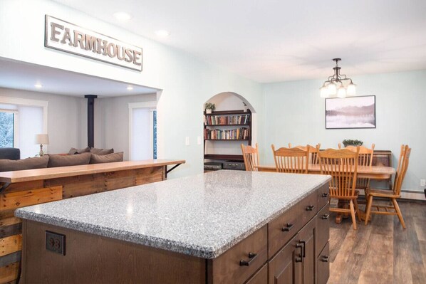 A kitchen with a granite countertop, wooden cabinets, and a dining area with a wooden table and chairs.