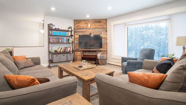 Ein Wohnzimmer mit Kamin, Bücherregal, Fernseher und großem Fenster.