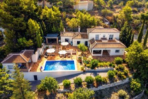 Eine Villa mit Pool, Sitzgelegenheiten im Freien und einem Garten.