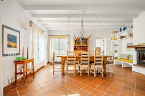 A dining area with a wooden table and chairs, a chandelier, and a bookshelf.