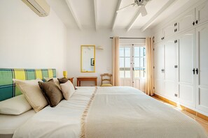 Ein Schlafzimmer mit Bett, Nachttisch, Spiegel, Kleiderschrank und einem Fenster mit Vorhängen.