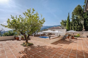 A rooftop patio with a swimming pool, outdoor seating, potted plants, and a view of the city and mountains. - Andalusia in the Heart (Cómpeta)