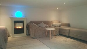 Una sala de estar acogedora con chimenea, un sofá y una mesita redonda.