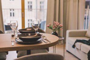 Ruokapöytä, jossa on kaksi lautasta, ruokailuvälineet ja viinilasiasetelma kahdelle.