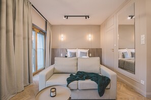 Ein modernes Hotelzimmer mit einer Sitzecke, einem kleinen runden Tisch und einem großen Spiegel.